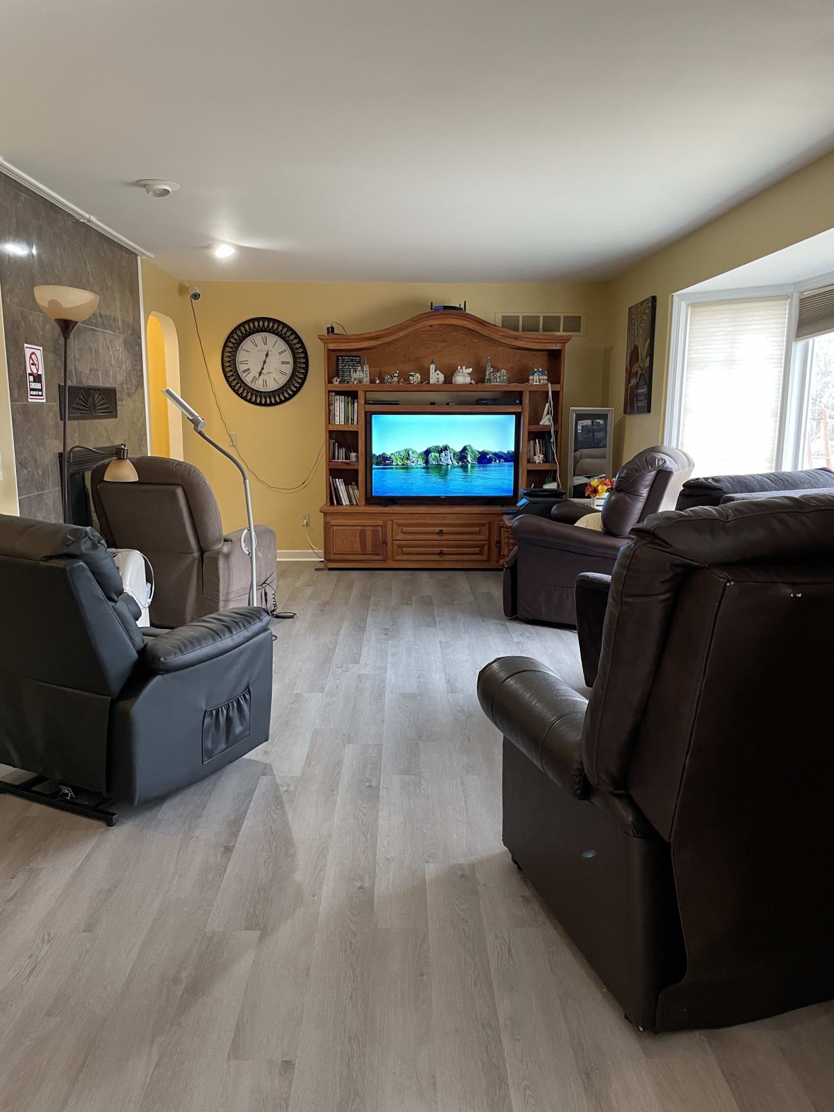 A cozy living room with recliner chairs facing a large television in an entertainment center.