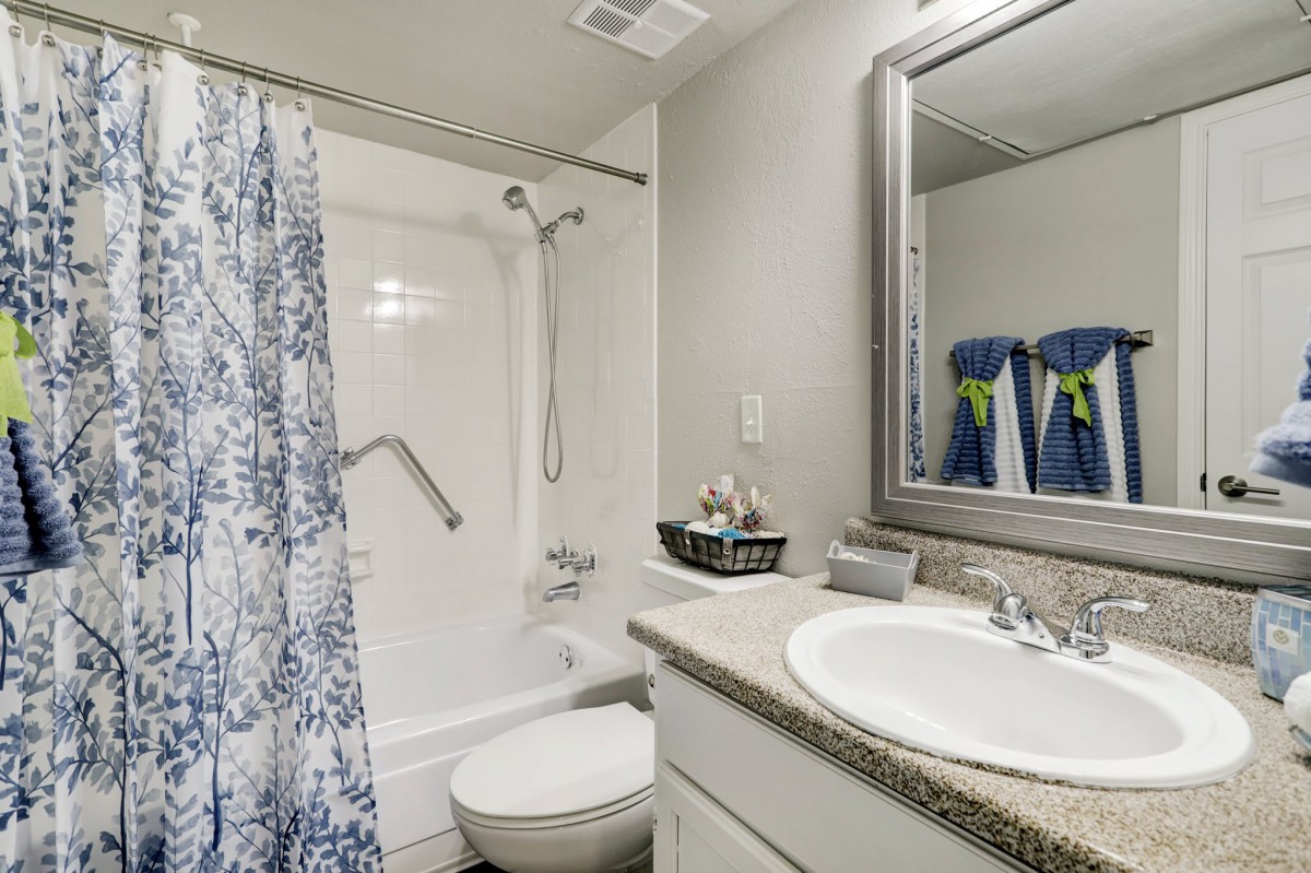 A modern bathroom with a shower curtain, sink, and mirror.