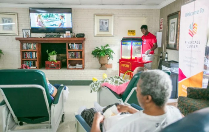 Elderly individuals in a nursing home enjoying leisure time with television and popcorn.
