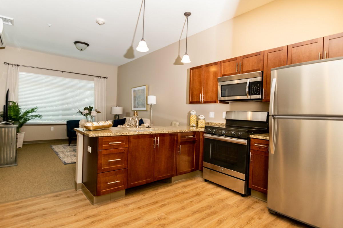 A modern kitchen with wooden cabinets, stainless steel appliances, and an open layout.
