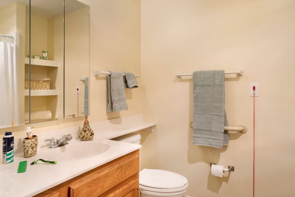 A clean and tidy bathroom with neatly arranged towels, a mirror above the sink, and decorative items on the countertop.