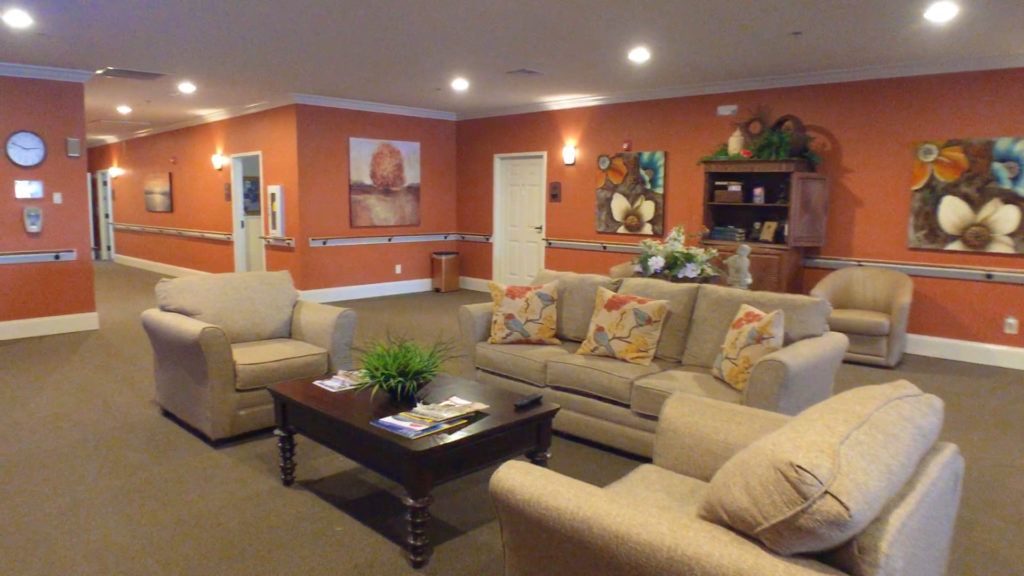 A cozy living room with comfortable sofas, a coffee table, and vibrant artwork on orange-painted walls.