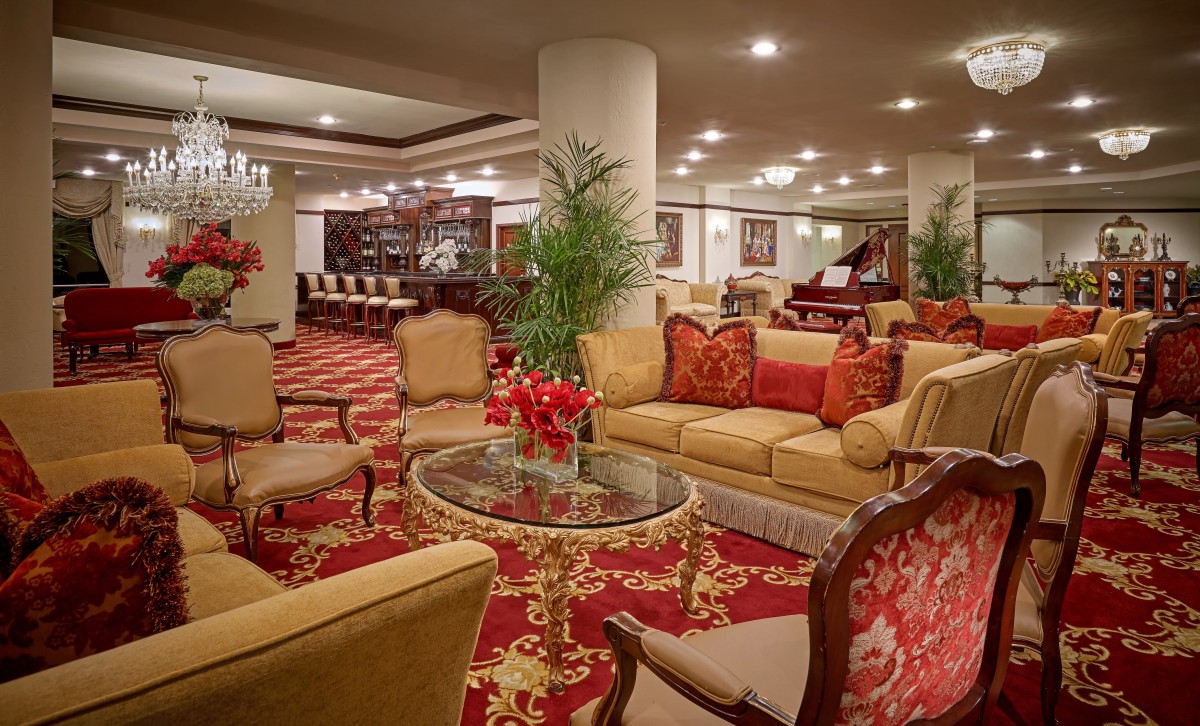 A luxurious hotel lobby featuring plush seating, elegant decor, and a grand piano.