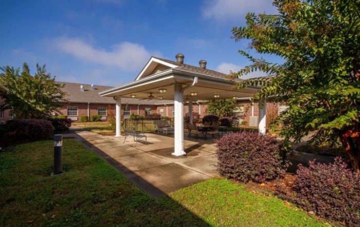 A sunny outdoor patio with a pavilion surrounded by well-maintained landscaping.