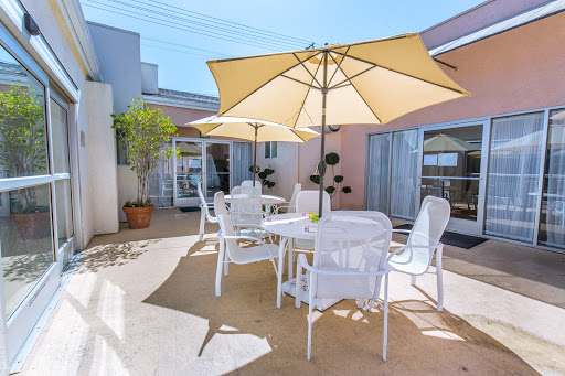 A serene outdoor patio area featuring white furniture and large umbrellas, perfect for enjoying a sunny day.