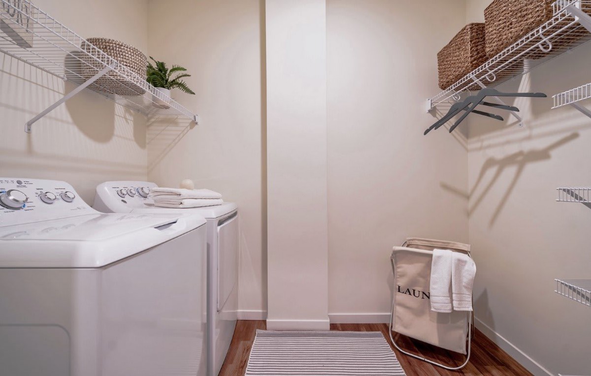 A neatly organized laundry room with a washing machine, dryer, and storage shelves.