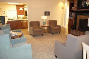 A cozy living room with comfortable chairs and a side table illuminated by a lamp.