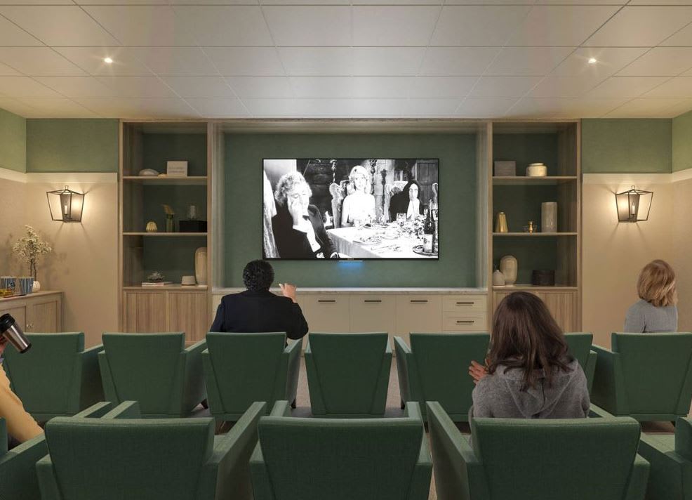 A cozy home theater with green chairs showing a classic black and white film.