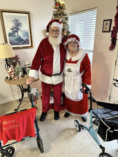 An elderly couple dressed in festive Christmas outfits, ready to spread holiday cheer!
