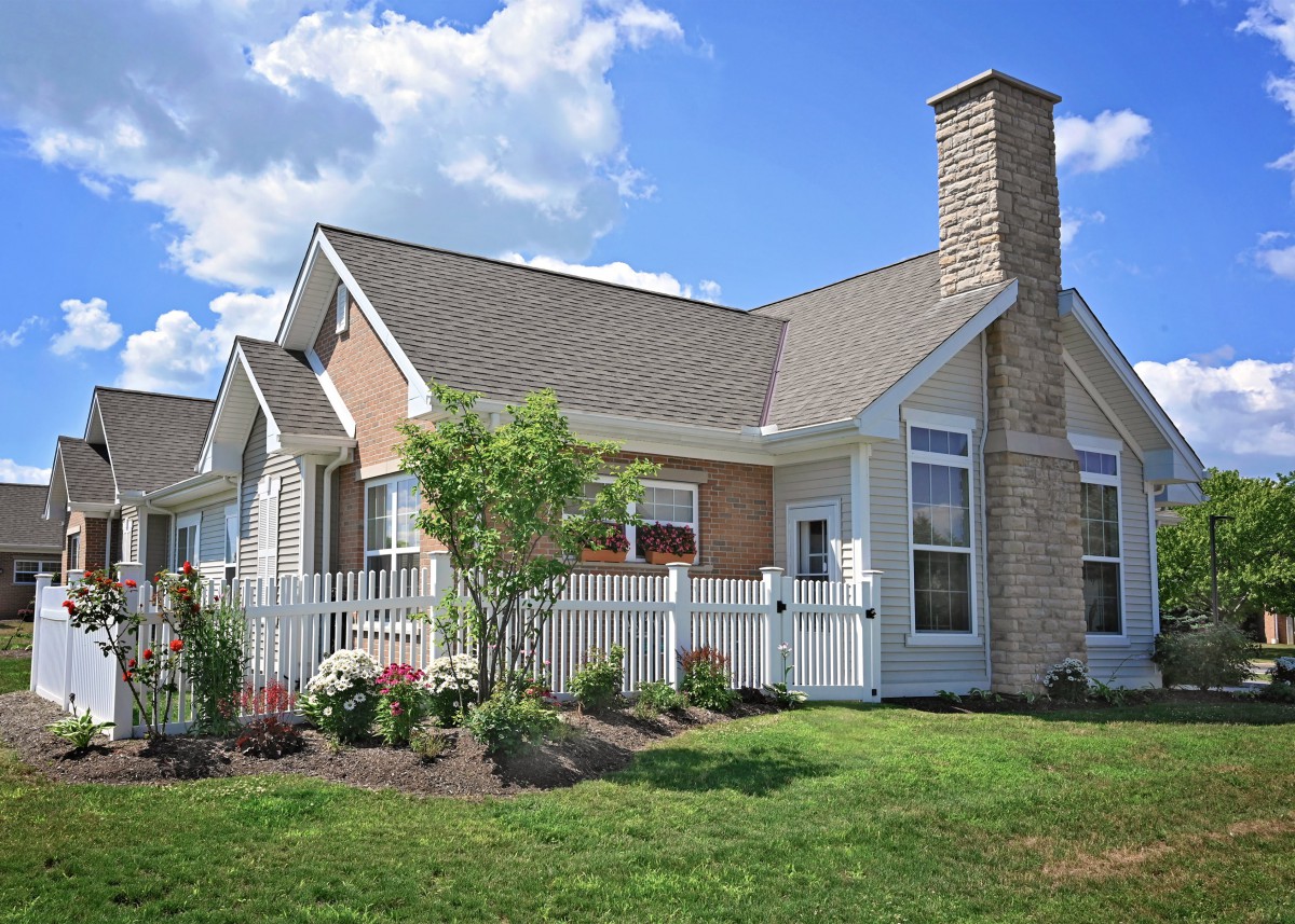 A charming single-story house with a well-maintained garden and white picket fence.