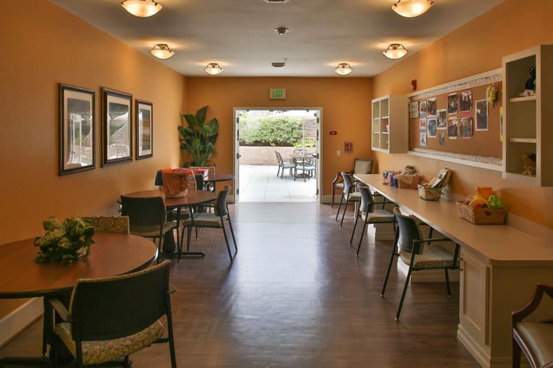 A cozy community room with tables and chairs arranged for social gatherings.
