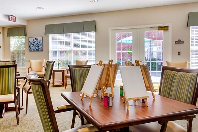 A bright art studio with easels and painting supplies set up on tables.