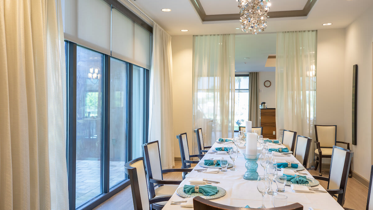 Elegant dining room with a beautifully set table and large windows letting in natural light.