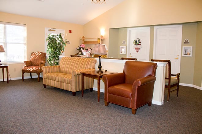 A cozy living room with a striped sofa, brown armchair, and a wooden table.