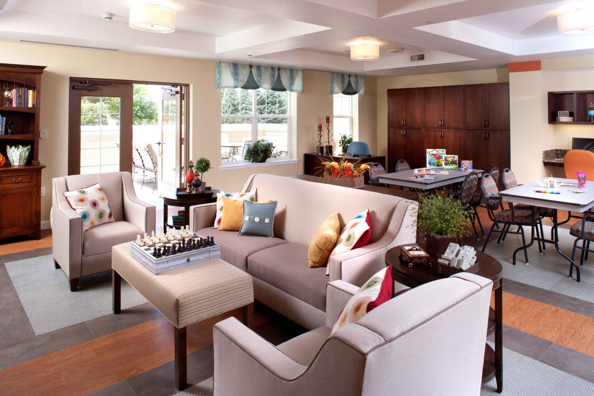 A cozy living room with modern furnishings, featuring a large sofa, decorative pillows, and ample natural light.