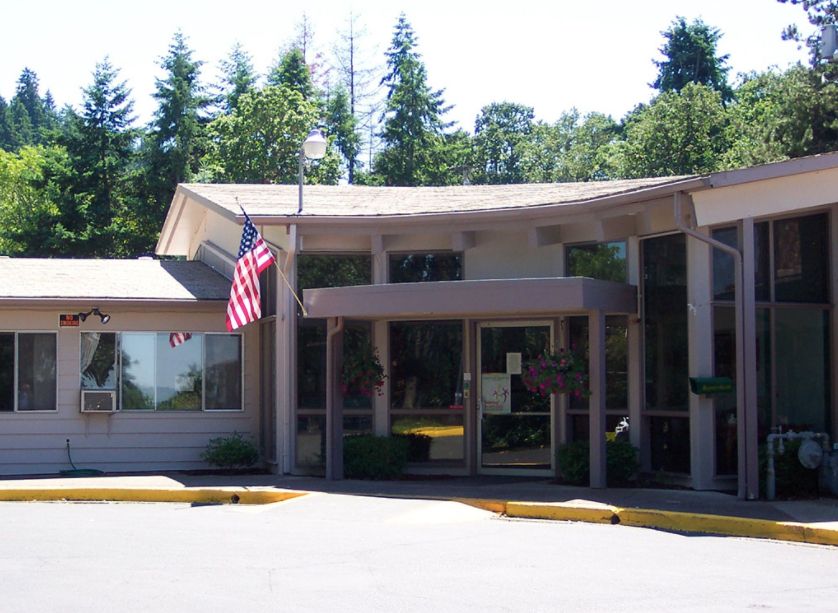 A building entrance with an American flag and surrounded by trees.