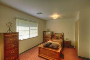 A cozy bedroom featuring wooden furniture and a large window.