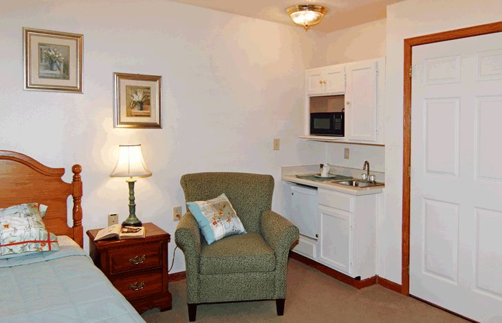 A cozy living area with an armchair and a kitchenette.