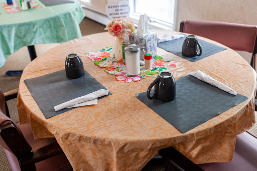 A well-prepared dining table featuring black mugs, placemats, and decorative flowers.