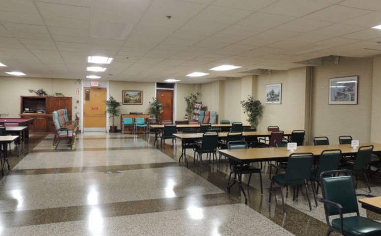 An empty meeting room with multiple tables and chairs arranged in rows.