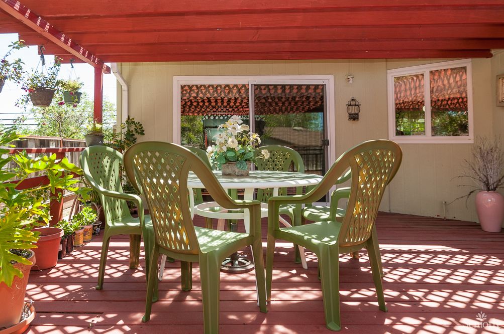 A sunny patio with green chairs and a table arranged for outdoor seating.