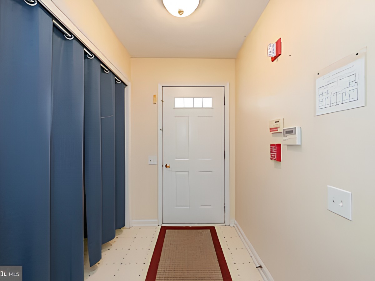 A hallway entrance with a door, blue curtains, and a rug on the floor.