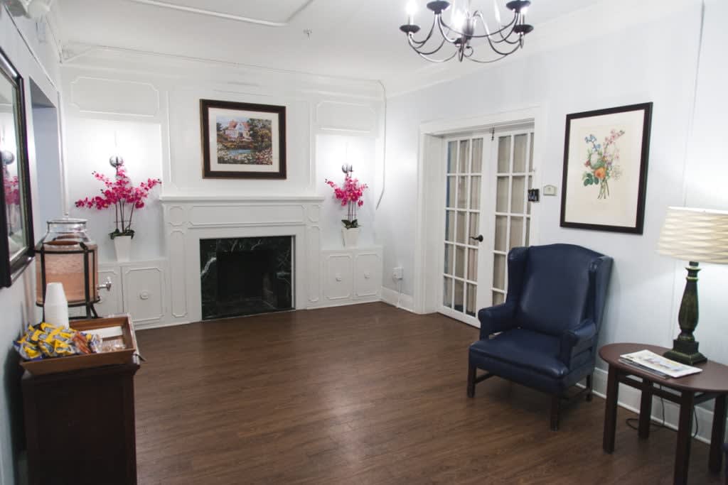 A cozy living room with a fireplace, elegant chandelier, and comfortable armchair.