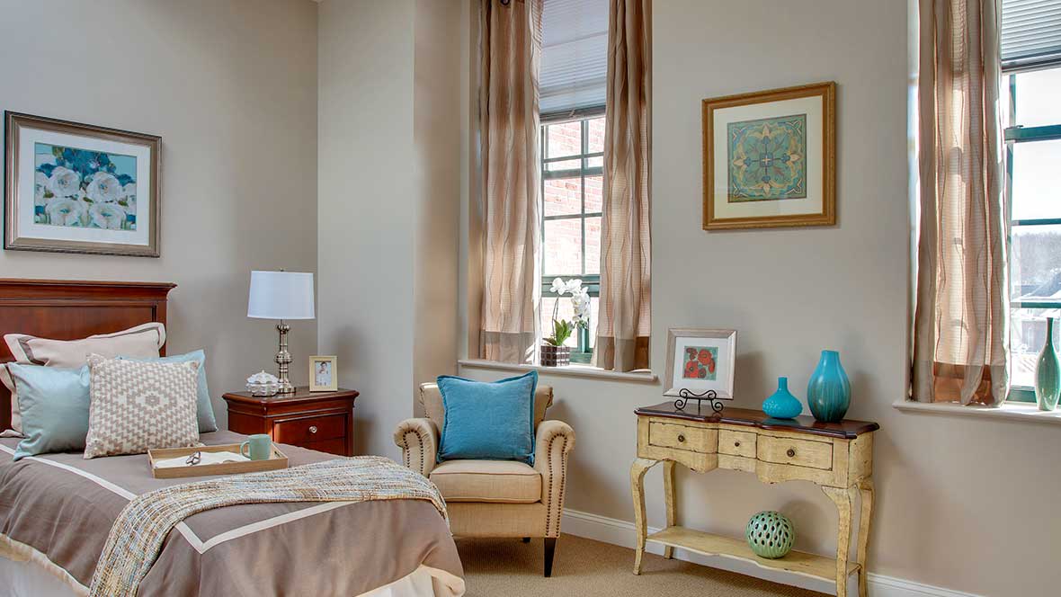 A cozy bedroom corner with a comfortable chair, side table, and window view.
