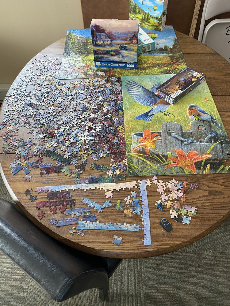 A jigsaw puzzle in progress on a round table, with pieces scattered and partially assembled.