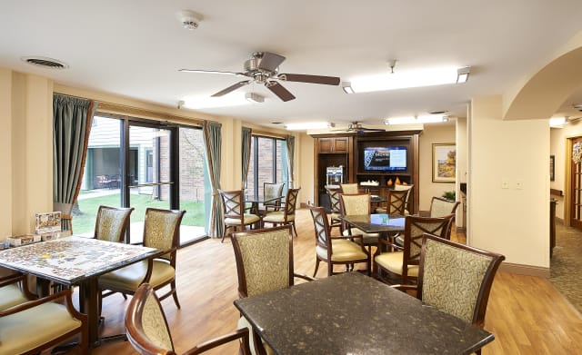 A bright and spacious dining area with tables and chairs, featuring a television and large windows.