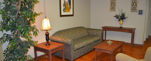 A cozy living room setup featuring a patterned sofa, wooden tables, and a lamp.