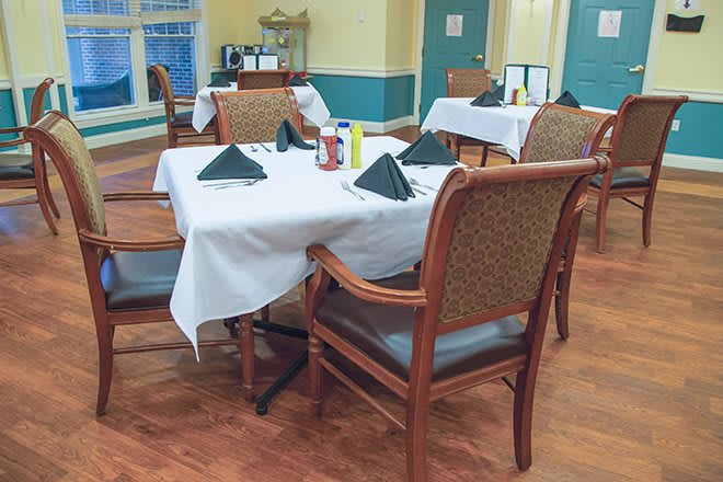 An elegantly set dining area with tables and chairs, featuring neatly arranged table settings.