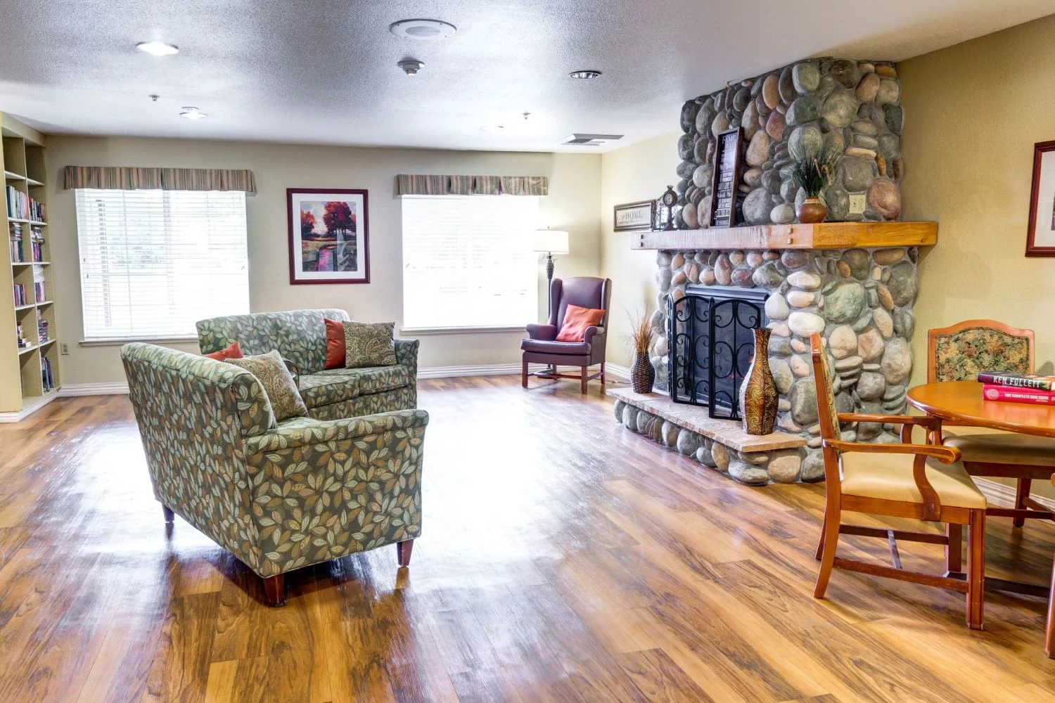 A cozy living room with a stone fireplace and wooden flooring.