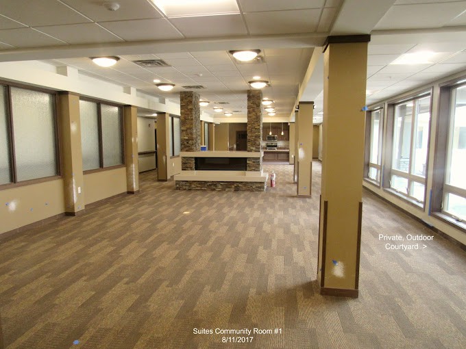 Spacious empty room with wooden flooring and large windows.