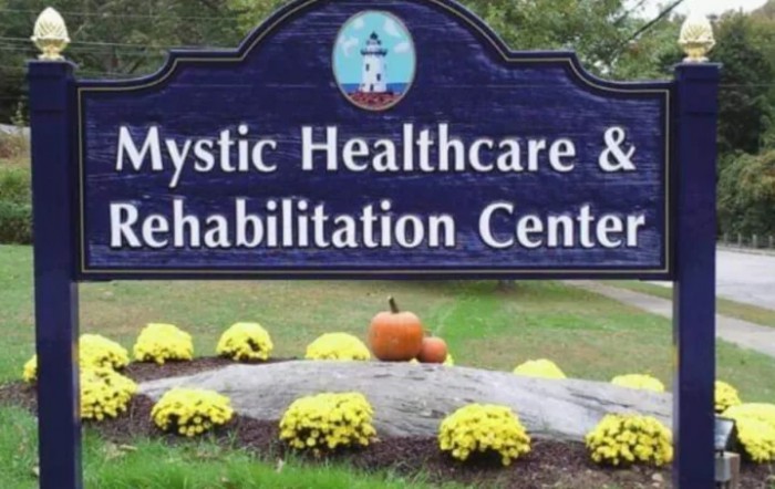 Sign for Mystic Healthcare & Rehabilitation Center with autumnal decorations.
