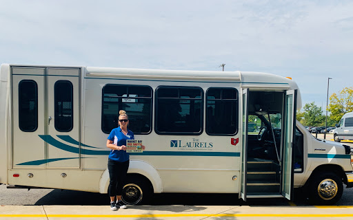 A woman stands beside a public transportation bus, ready for her next journey.