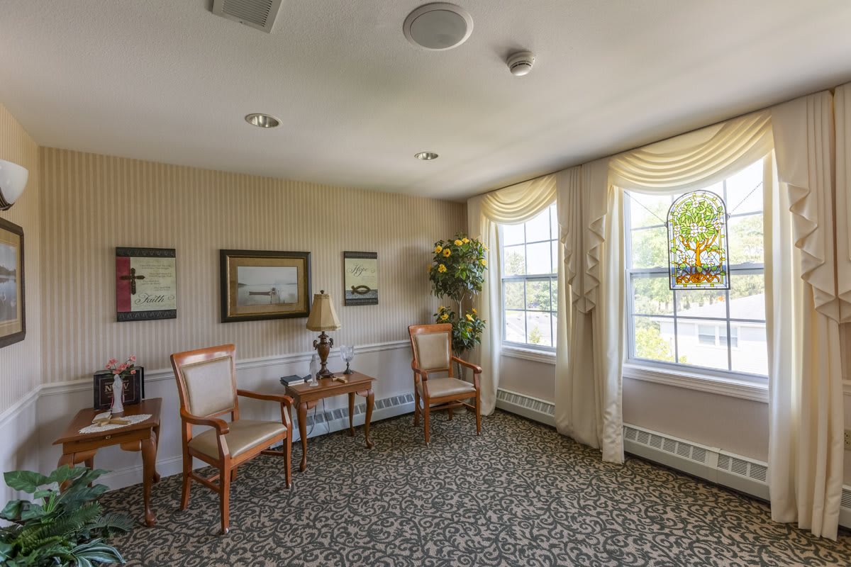 A cozy room with chairs, a small table, and large windows letting in natural light.