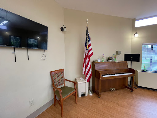 A cozy room featuring a piano, an American flag, a television, and a chair.