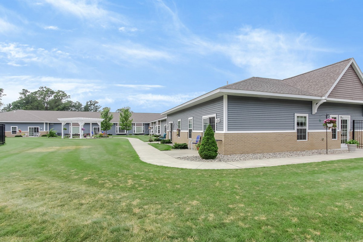 A residential building with a neatly maintained lawn and walkway under a clear blue sky.