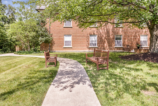 A peaceful outdoor space featuring a paved walkway leading to seating surrounded by greenery.