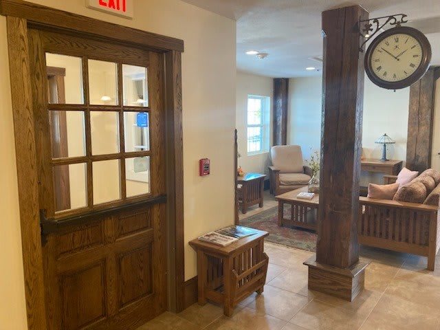 A cozy waiting area with comfortable seating and a wooden door, featuring warm lighting and modern decor.