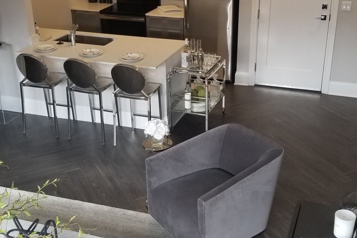A modern kitchen with a stylish countertop, bar stools, and a cozy armchair.