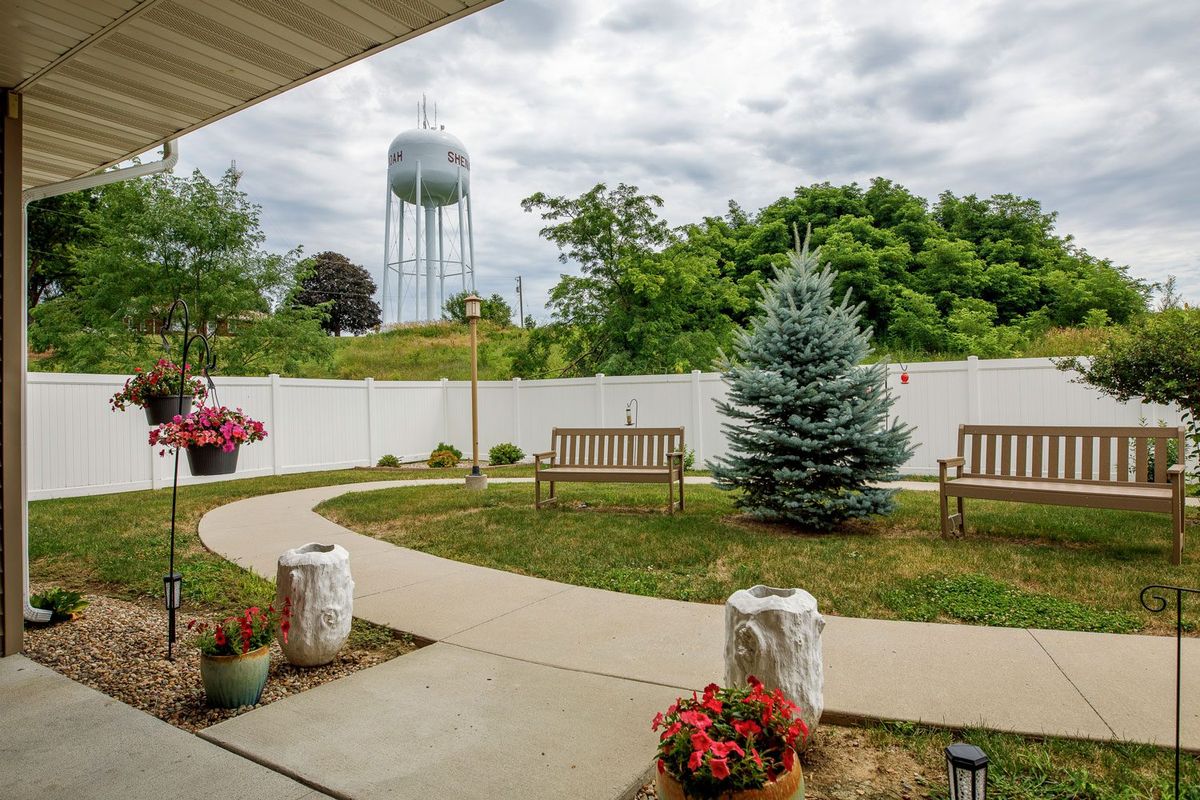A serene backyard garden with benches and a view of a water tower.