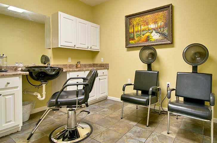 A cozy hair salon setup with styling chairs, a hair dryer, and wall art.