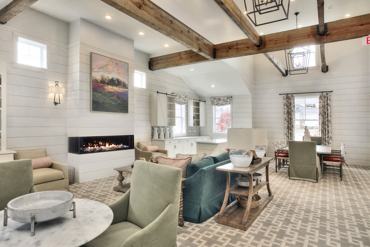 A modern living room with stylish furniture, a fireplace, and exposed wooden beams.