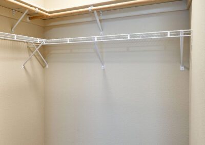 An empty closet with white wire shelves on beige walls.