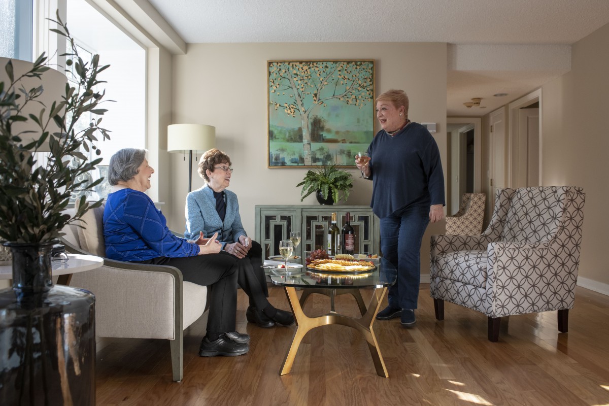 Three people engaging in conversation in a cozy living room.