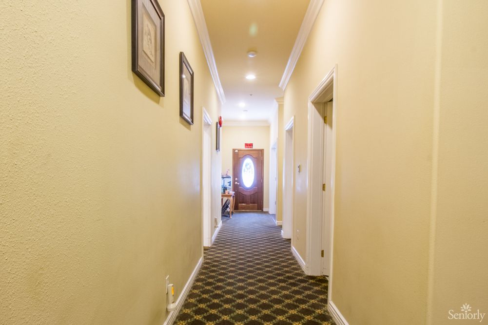 A well-lit hallway with carpeted flooring and framed pictures on the walls.
