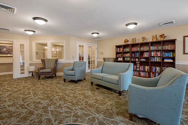 A cozy library seating area with armchairs and couches, surrounded by bookshelves.