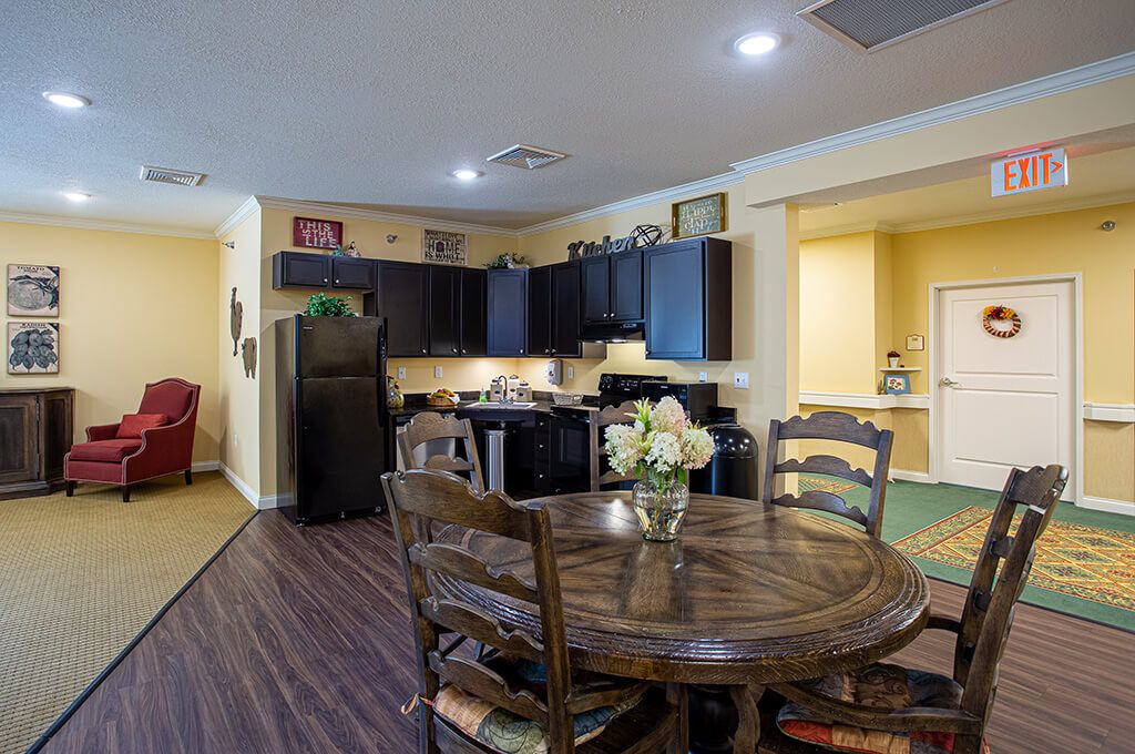 A cozy kitchen and dining area with dark cabinets and a wooden table adorned with flowers.